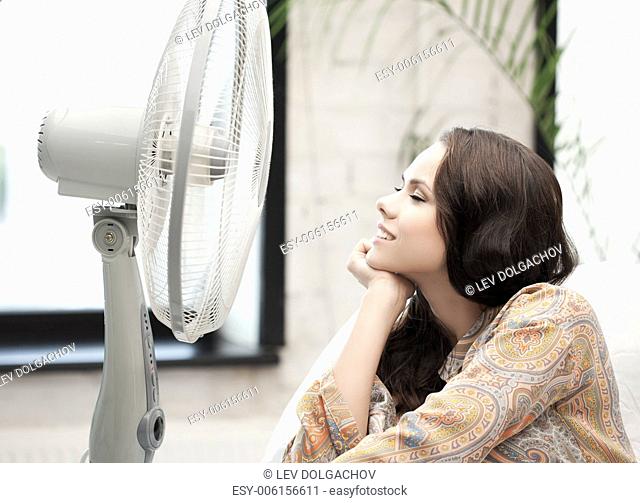 home technology concept - happy and smiling woman sitting near ventilator