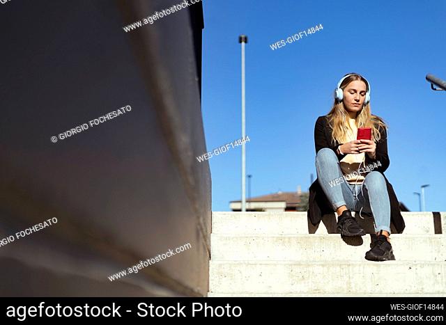 Young woman using smart phone sitting on steps