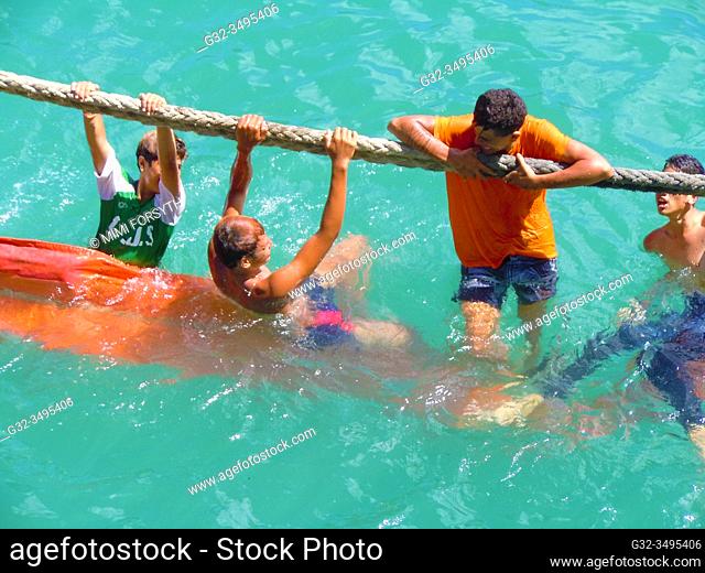 boys play on ship's rope, Hakahau harbor, Ua Pou, Marquesas, French Polynesia