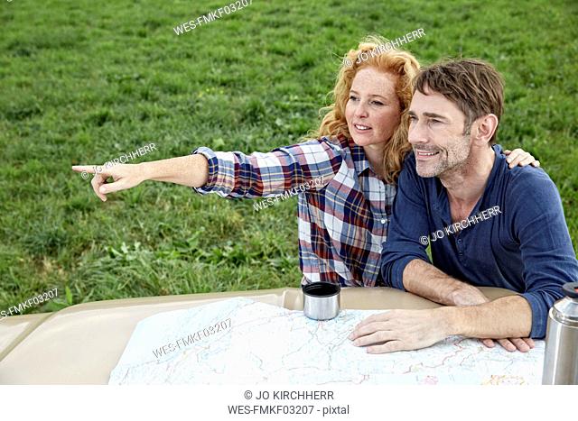 Couple at pick up truck with map with woman pointing