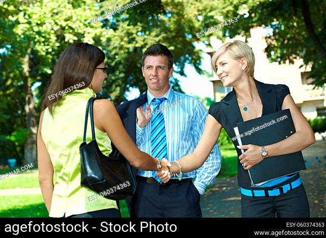 Young businesspeople meeting in park, shaking hands