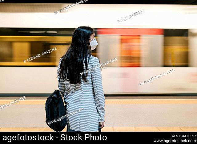 Woman waiting for her train at metro station during pandemic