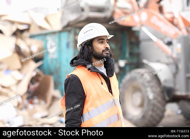 Technician with beard and helmet working in a recycling yard, Freiburg, Baden-Württemberg, Germany, Europe