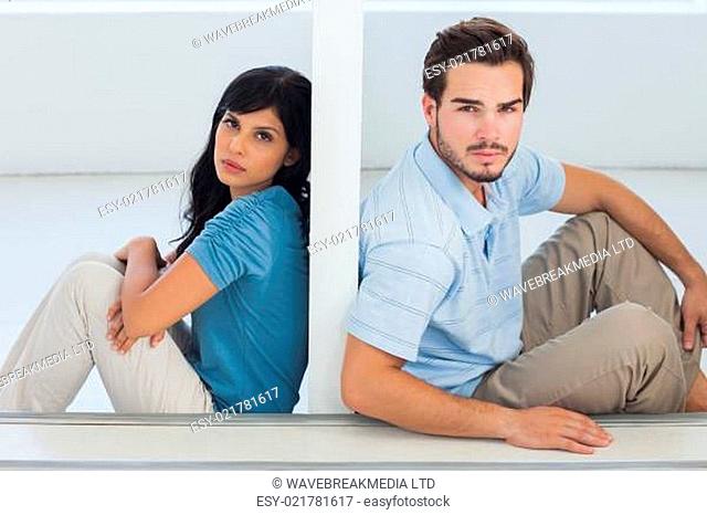 Unhappy couple are separated by white wall