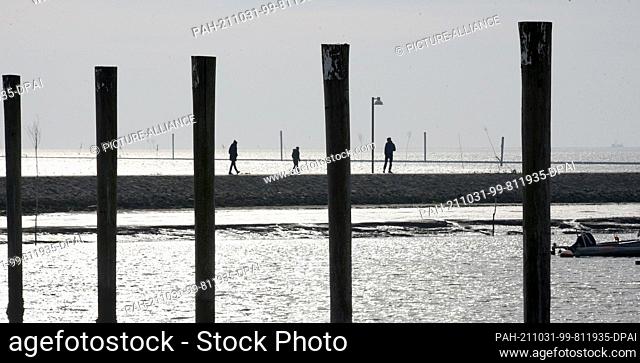 18 October 2021, Lower Saxony, Juist: People walk across the pier to the sea mark on the East Frisian island of Juist, one of the island's landmarks