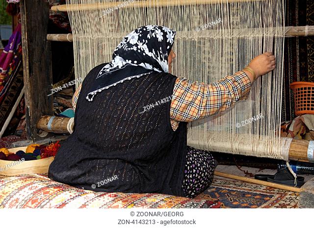 Teppichweberin sitzt an einem traditionellen Handwebstuhl, Göreme, Kappadokien, Türkei / Female carpet weaver sitting at a traditional hand loom, Goreme