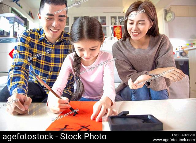 happy chinese new year. family and little girl writing calligraphy for celebration