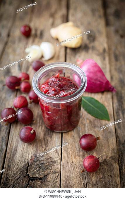 Gooseberry chutney in a glass surrounded by ingredients