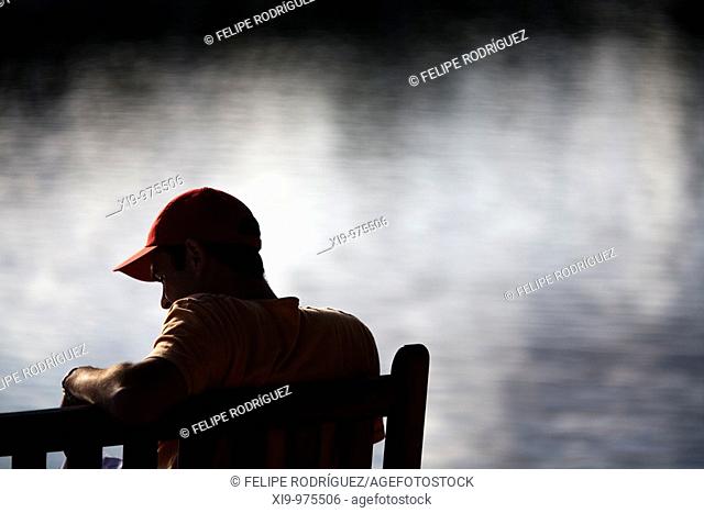 Young man sitting on a bench by the sea, Conleau island, town of Vannes, departament of Morbihan, region of Brittany, France