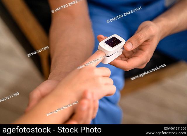 Cropped photo of a healthcare worker putting a pulse oximeter on a patient index finger
