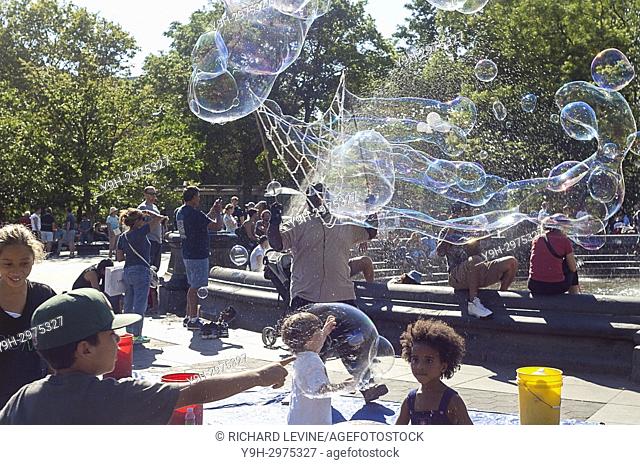 A busker in Washington Square Park in New York entertains visitors with giant bubbles on Sunday, July 30, 2017