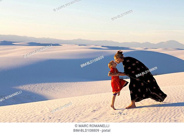 Caucasian mother and daughter kissing in desert