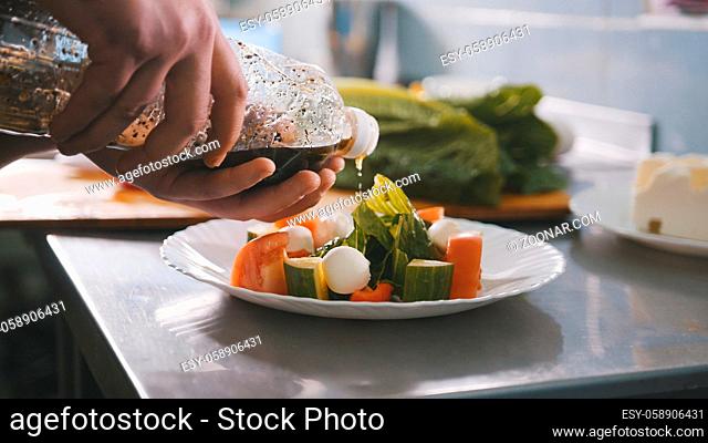 Chef serves salad on the plate in restaurant, close-up view