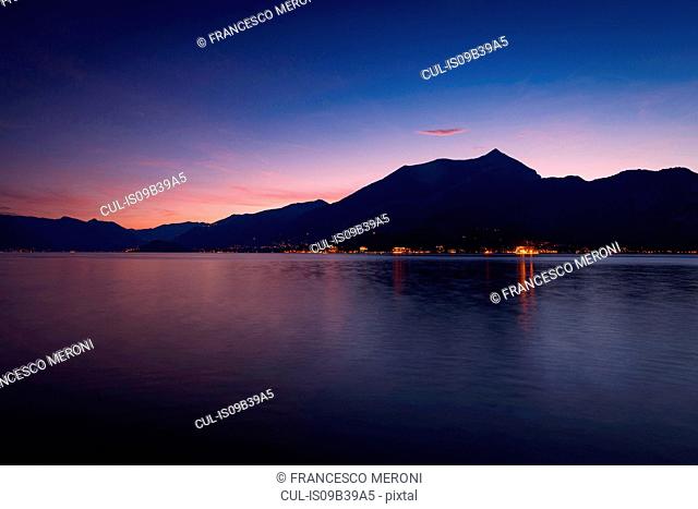 View of silhouetted mountains over Lake Como at night, Bellagio, Italy