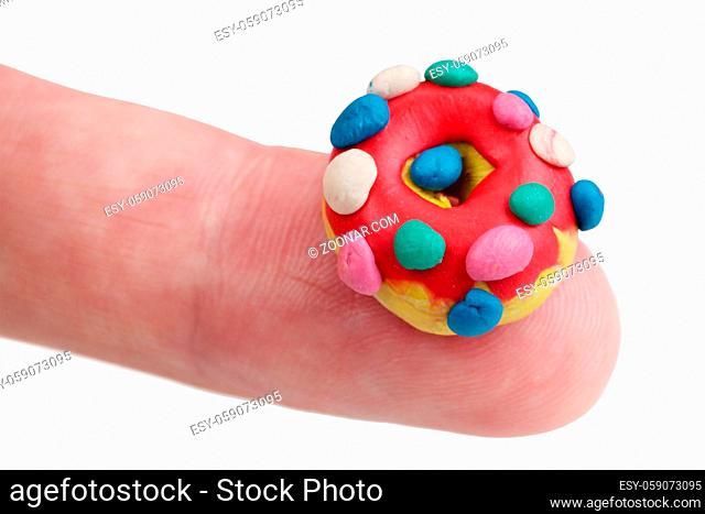 In the future we will eat this concept - mini donut made of clay plasticine on finger. Isolated on white studio macro