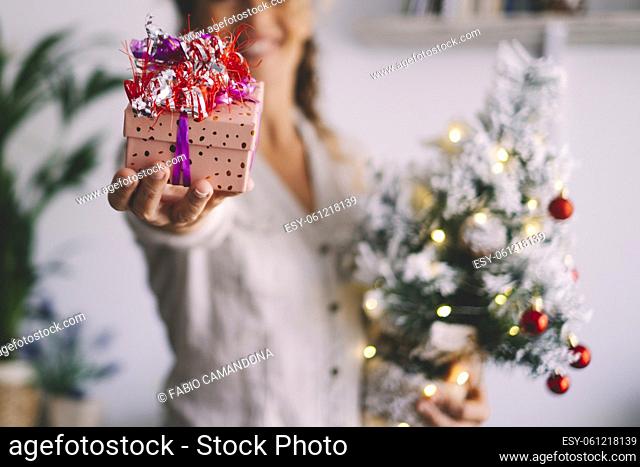 Gift exchange christmas holidays people concept. Close up of present with xmas decorations and happy female with tree in background