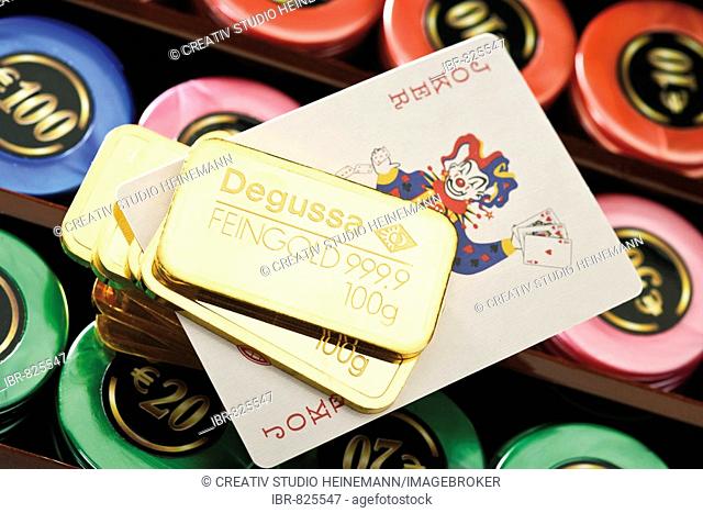Gold bars on a roulette table with casino chips and a joker card