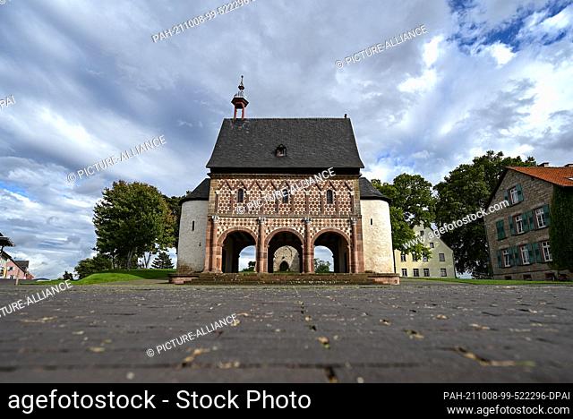29 September 2021, Hessen, Lorsch: The so-called Gate Hall or King's Hall with its world-famous colourful sandstone façade rises in front of a park-like area...