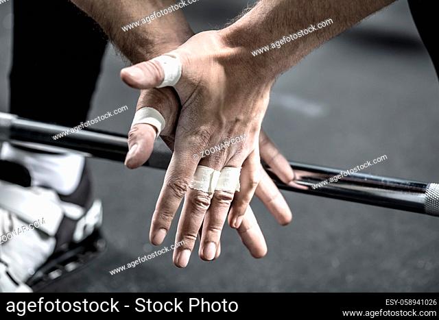 Macro photo of man's hands with white plaster on the fingers. Hands are in front of the chrome crossbar and guy's legs. Horizontal
