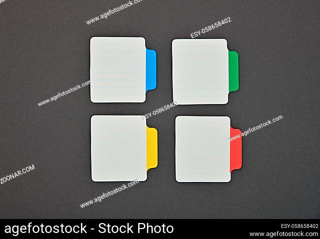 Close up four blank white paper notes with colorful labels over grey background
