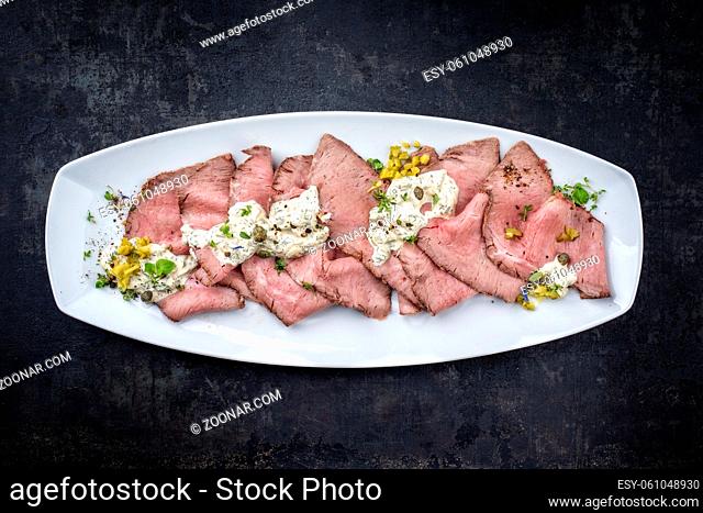 Traditional lunch meat with sliced cold cuts roast beef and remoulade as top view on a white plate