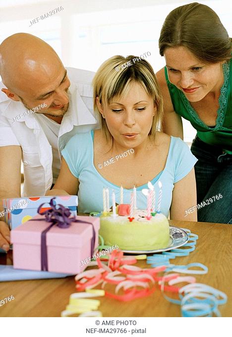 A woman blowing out candles on a birthday cake