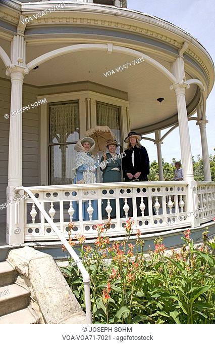 Women in Victorian dresses standing on porch of Faulkner Farm and Victorian home in Santa Paula, CA