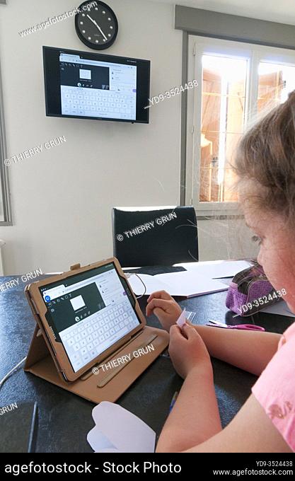 France, Loiret (45), Covid-19 French lockdown on 04/27/2020, young girl of 7 years old in CE1 during virtual school class at home using tablet remote connection...