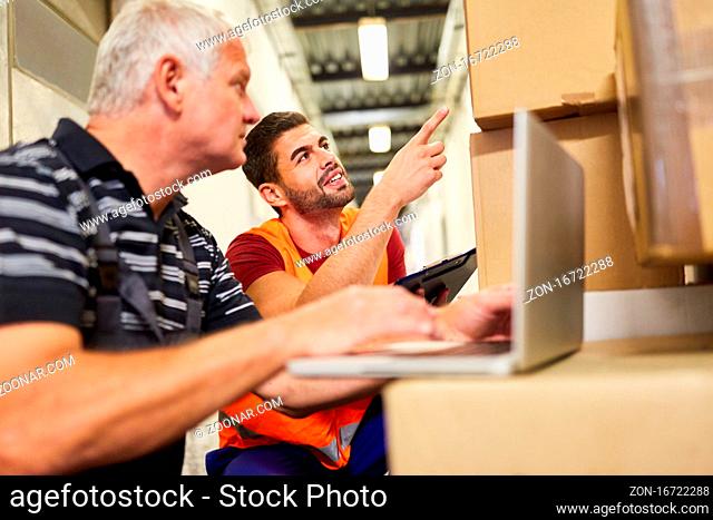 Zwei Lagerarbeiter an Laptop PC mit Paketen im Onlineshop vor dem Versand
