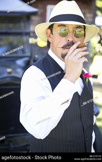 Handsome 1920s dressed man near vintage car smoking A cigar