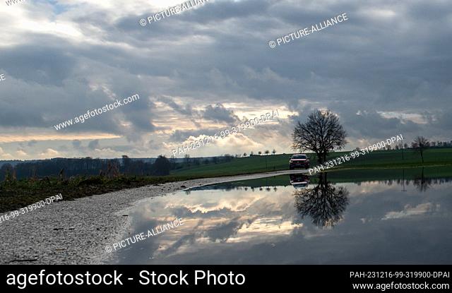 16 December 2023, Bavaria, Alerheim: A car is parked on a road that is still partially flooded by the Wörnitz. The river levels are falling and the flood...