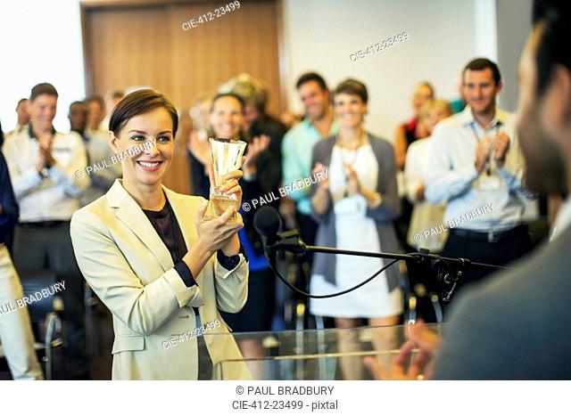 Businesswoman giving award to businessman, colleagues in background