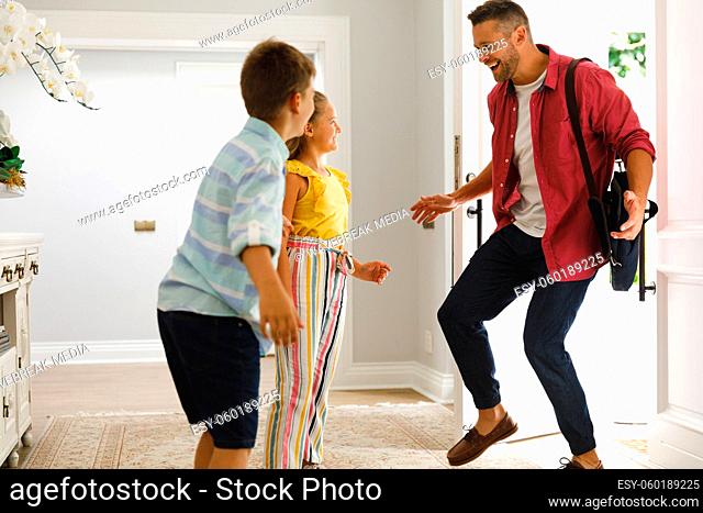 Happy caucasian father returning home with daughter and son smiling and greeting him at front door