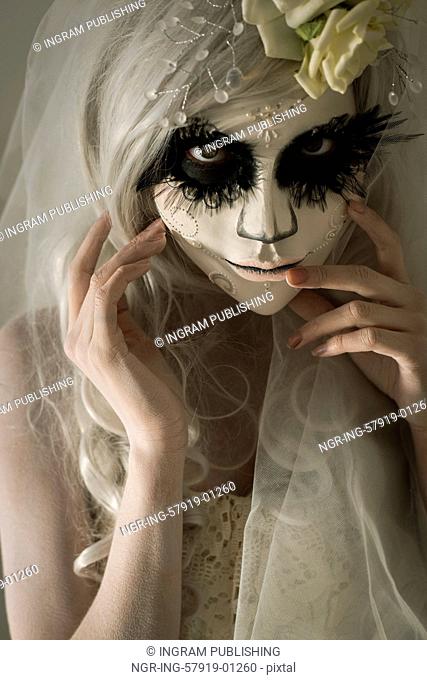 Halloween witch. Beautiful woman wearing santa muerte mask and wedding dress. Dead widow in grief
