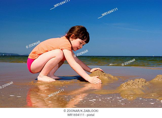 Little girl child kid playing doing sand castle