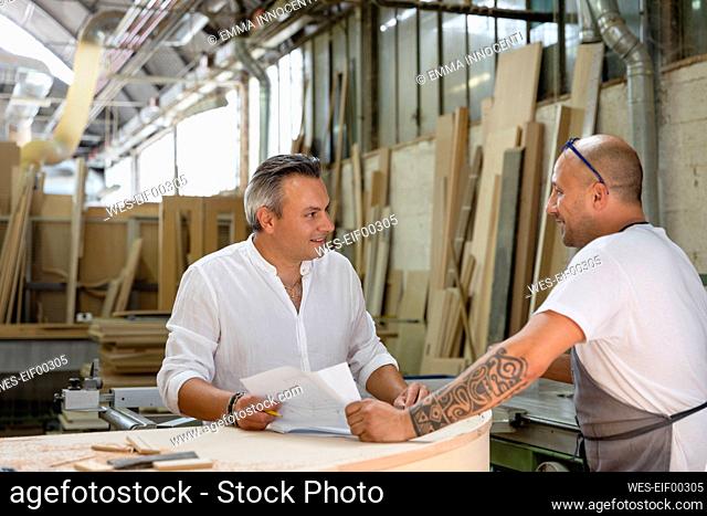 Project manager talking to coworker while standing at factory