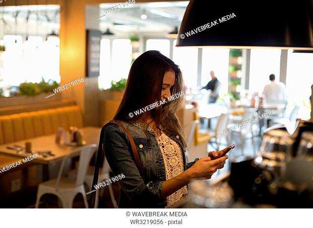 Woman using mobile phone in cafe
