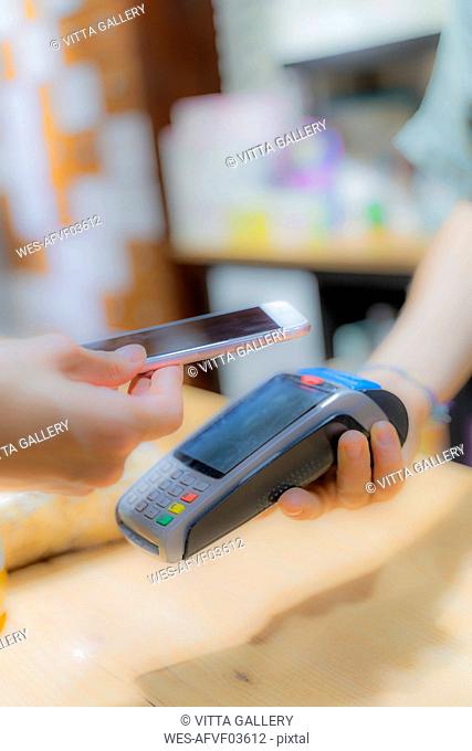 Customer paying cashless with smartphone in a shop