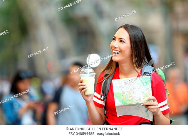 Happy teen tourist sightseeing holding a paper map in the street