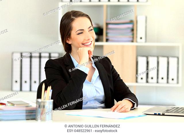 Happy office worker thinking and looking at side at workplace