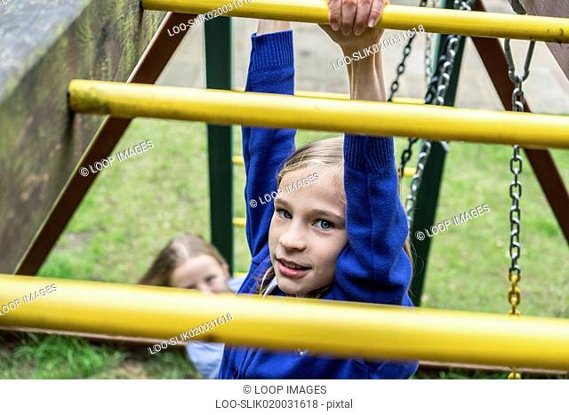 A ten year old girl in school uniform climbing on playground apparatus