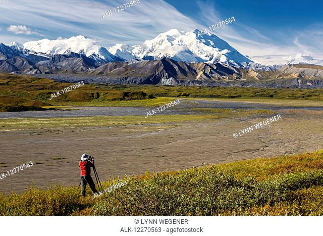 A male tourist photographs Mt. McKinley and the Thorofare River valley in Denali National Park, Interior Alaska, USA