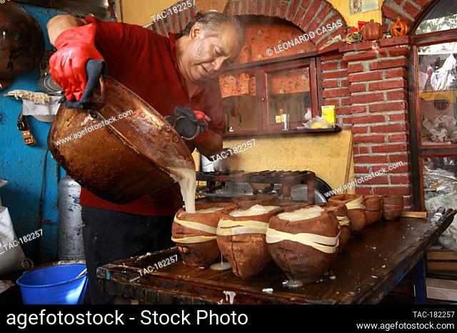 MEXICO CITY, MEXICO - OCTOBER 23: A person cooks a mixture of sugar with water into a clay mold in the shape of a skull during the making of the traditional...