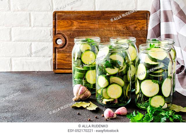 Canned zucchini and fresh vegetables for the winter. Sliced zucchini with parsley and garlic, homemade vegetables preserves in glass jar