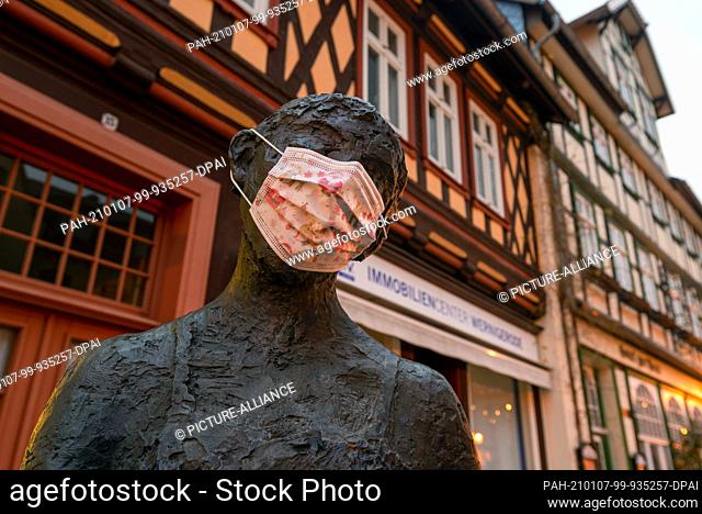 26 December 2020, Saxony-Anhalt, Wernigerode: Someone has put a mask on a bronze figure in the historic old town. Normally