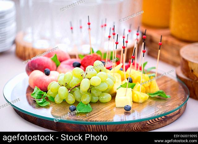 Festive food. Canape with fruits. bunch of grapes, juicy peaches, fresh mint, sweet pineapple, bright strawberry. The taste of summer and fresh fruit
