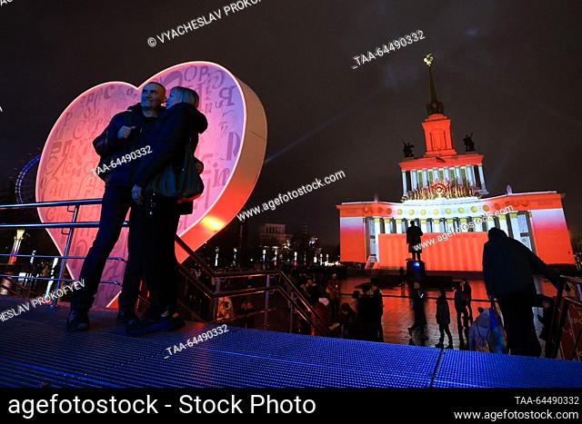 RUSSIA, MOSCOW - NOVEMBER 6, 2023: A heart-shaped installation and a statue of Russian revolutionary Vladimir Lenin are seen by an illuminated Central pavilion...