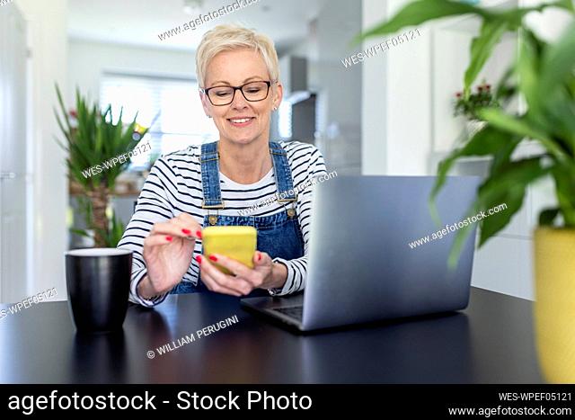 Female professional using smart phone while sitting with laptop at desk