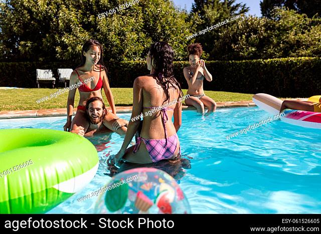 Diverse group of friends having fun and carrying on shoulders in swimming pool