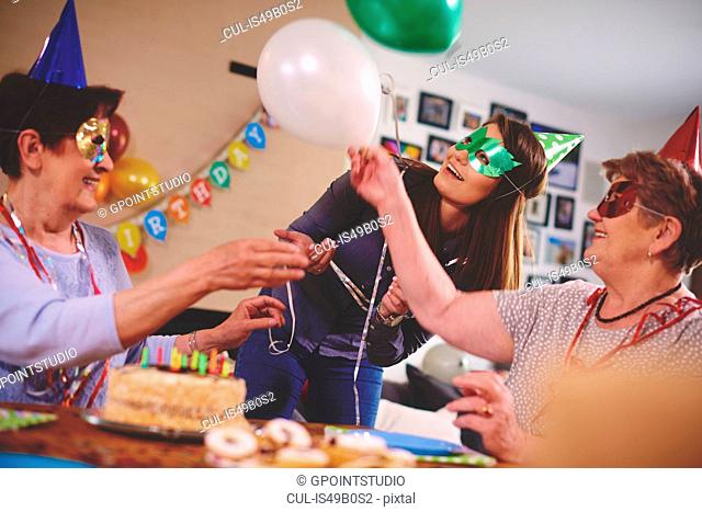 Senior women waving balloons at birthday party